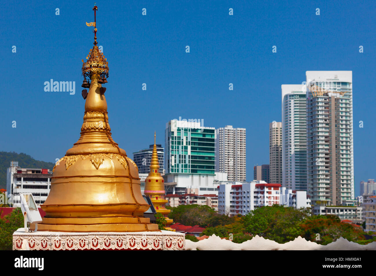 Golden buddhist stupa on modern city buildings background. Pagoda exterior of ancient Burmese buddhist temple Dhammikarama in Georgetown on Penang Stock Photo