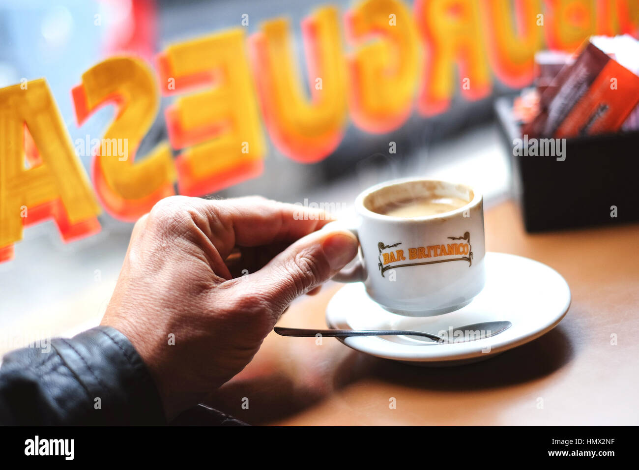 Ein Mann sitzt in einem Lokal und hält eine Kaffeetasse in der Hand (Nahaufnahme) Stock Photo