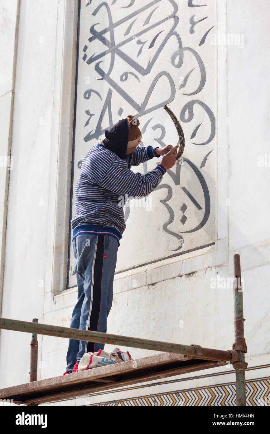 AGRA, INDIA - JANUARY 13, 2015 : A craftsman on a scaffold repairing calligraphic inscriptions in the marble of the north east minaret at the Taj Maha Stock Photo