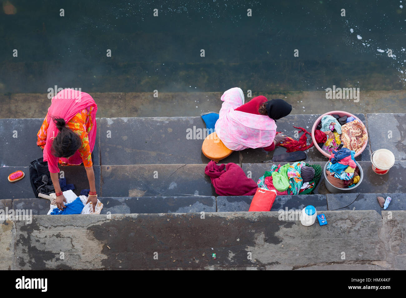 UDAIPUR, INDIA - JANUARY 16, 2015 : Aerial view of two women washing clothes on the steps of Lal Ghat next to Lake Pichola. Stock Photo