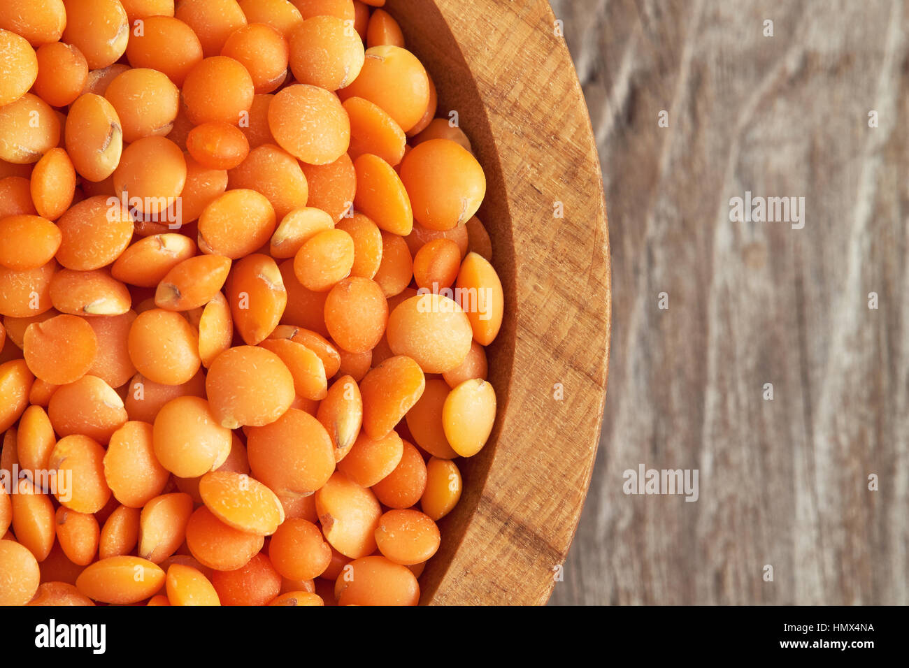 Raw uncooked red lentils in wooden bowl on rustic background. Top view with copy space Stock Photo