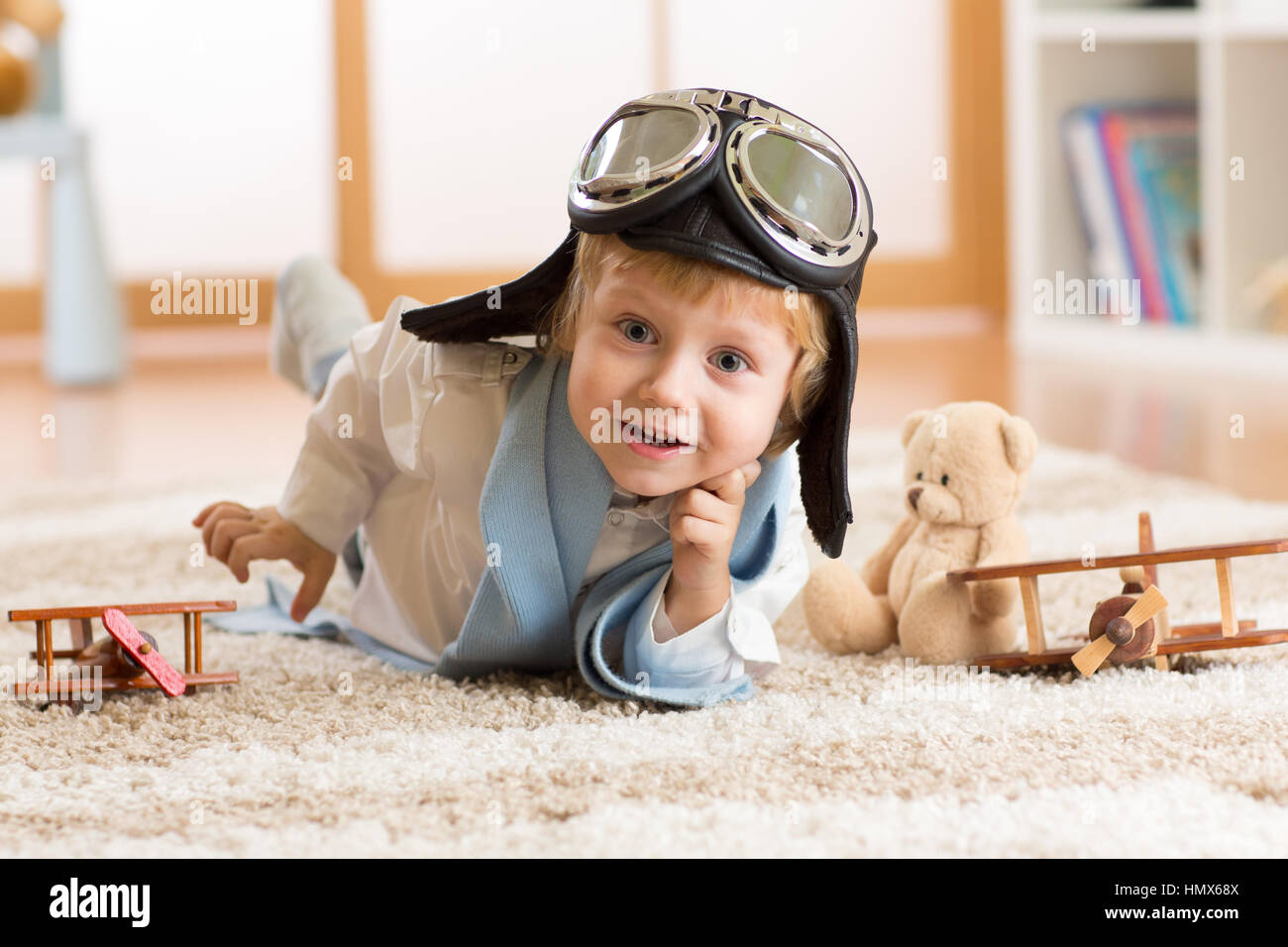 portrait of kid boy playing with wooden airplanes on carpet in nursery room Stock Photo