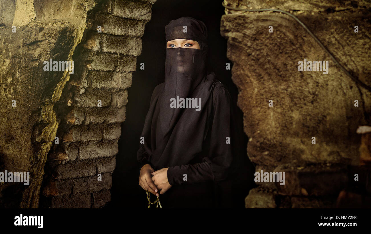 TAIPING, PERAK - AUGUST 6 2016 : A niqab or burqa girl standing with rosary beads in her hand infront of a cave. Stock Photo