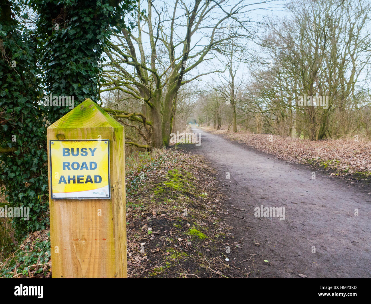 Disused railway line, now public footpath, crossing busy road in Cheshire UK Stock Photo