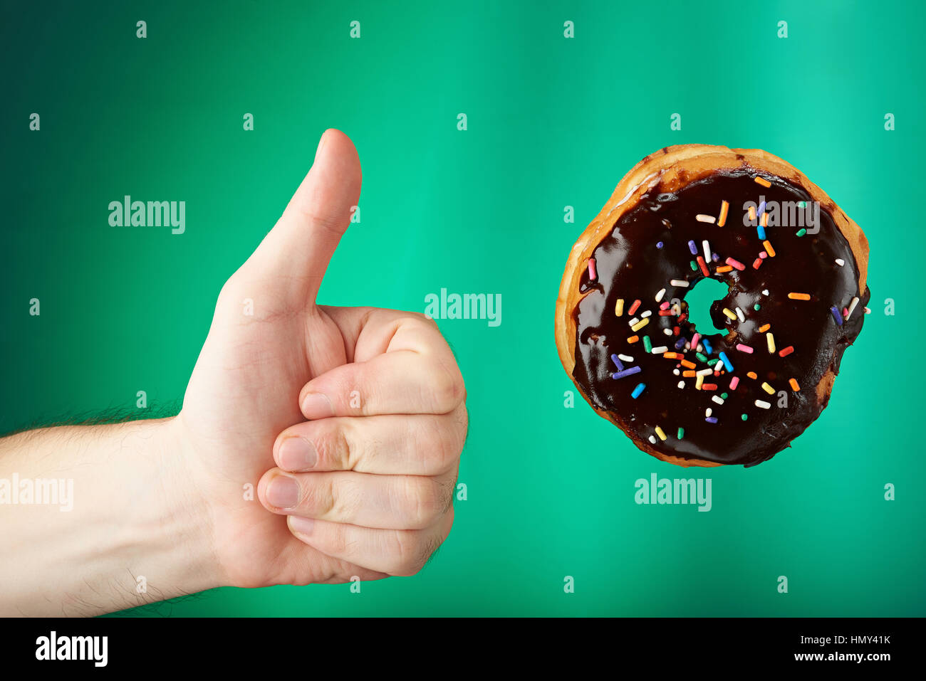 Thumb up to sweet chocolate donut  isolated on green Stock Photo