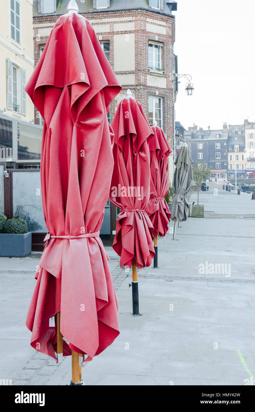Frosty red rolled up umbrellas outside a cafe in Honfleur, Normandy Stock Photo