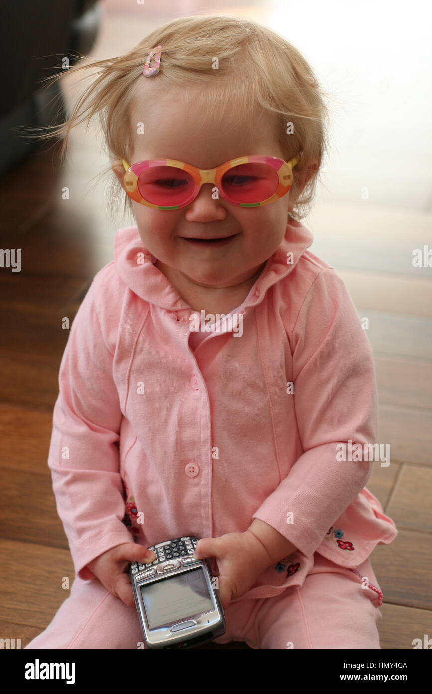 Baby girl laughing playing with sunglasses and a phone funny concept, laughing happy funny child, messing silly, goggles phone childhood fun Stock Photo