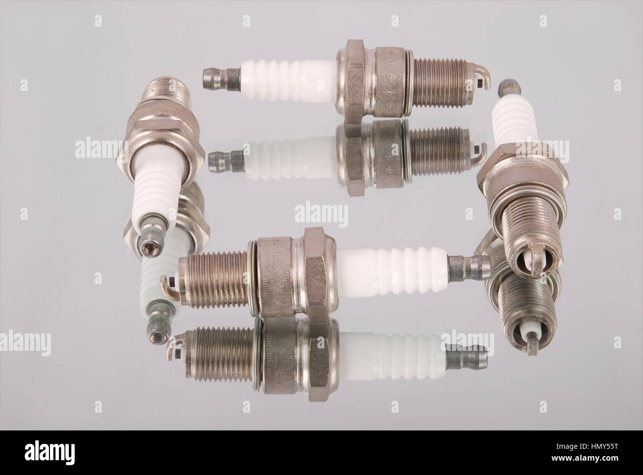 Four new spark plugs on a mirror background Stock Photo