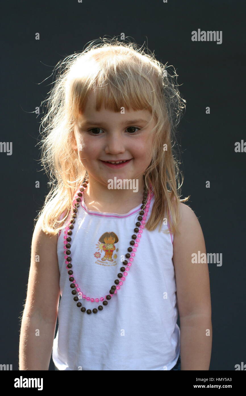 Little Girl With Blonde Hair And A Fringe Smiling Wearing Beads