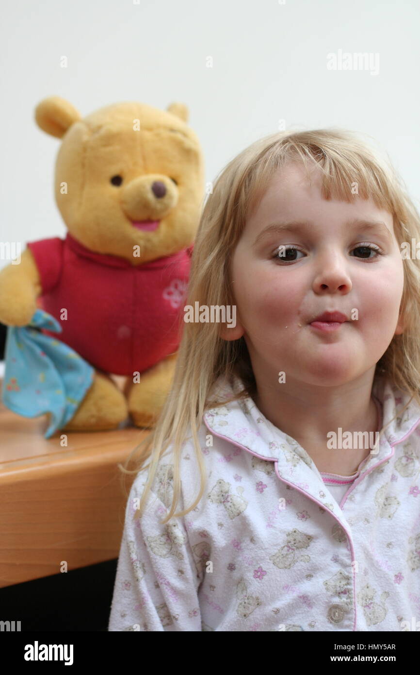 Little three year old girl playing with winnie the pooh childhood fun, innocence concept, happy, innocent sweet blonde child pjs happy messing Stock Photo