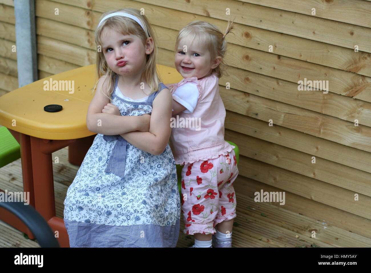 Children playing together in the garden, making a funny face kids thinking child thinking, messing goofing sisters sisterly love concept Stock Photo