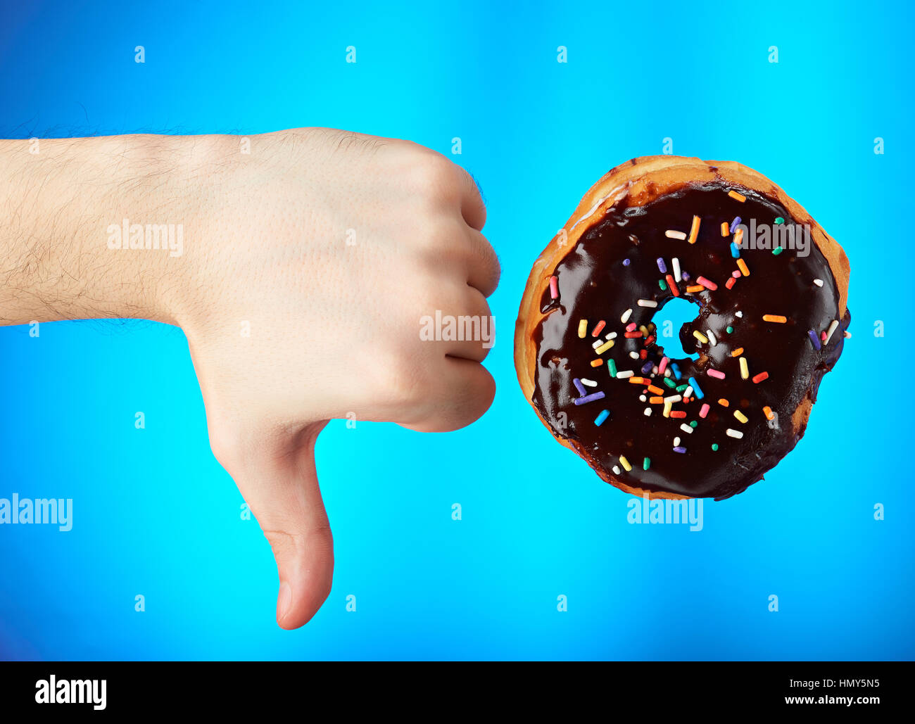 donut with thumb down isolated on blue background Stock Photo