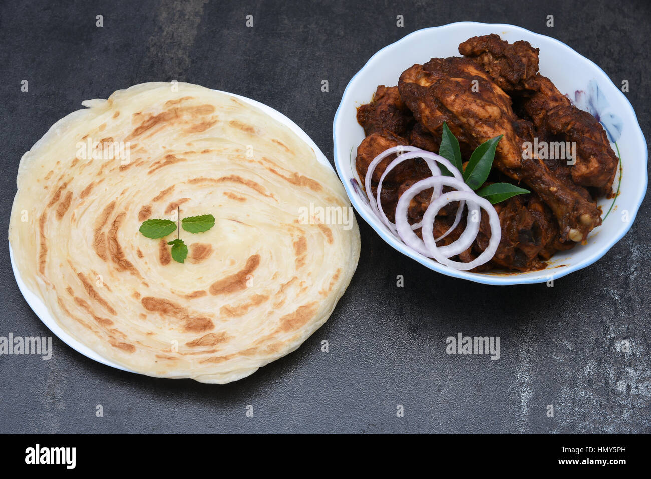 Kerala paratha / porotta / roti / parotta / barotta / naan layered flat bread maida wheat flour with hot spicy chicken curry Stock Photo