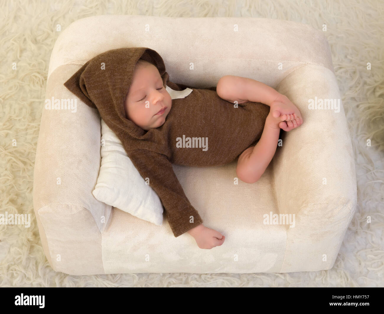One week old newborn baby of mixed race relaxing on a soft couch Stock