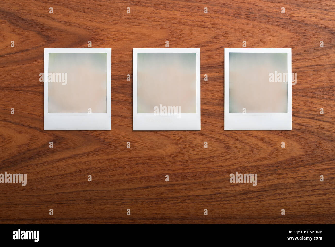 Blank instant print photographs on wooden table. Three Objects in a row. Stock Photo