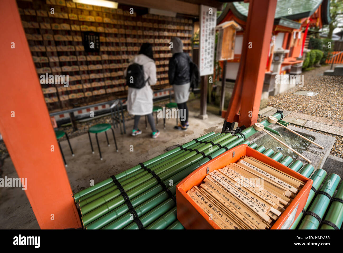 Two tourists looking at small wooden plaques with prayers and wishes at Fushimi Inari Taisha (Shinto shrine), Kyoto Stock Photo