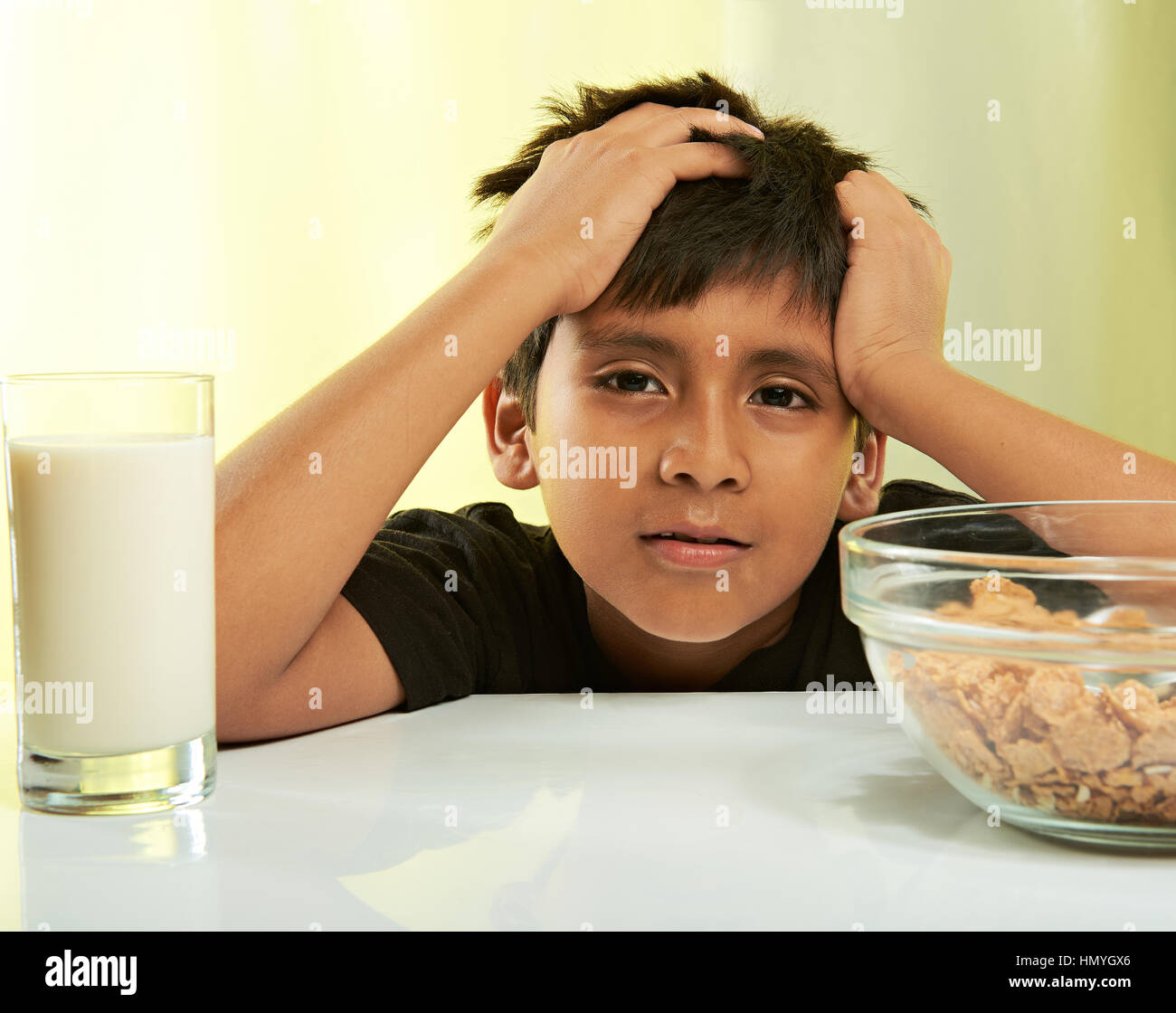 bored boy at breakfast isolated on yellow Stock Photo