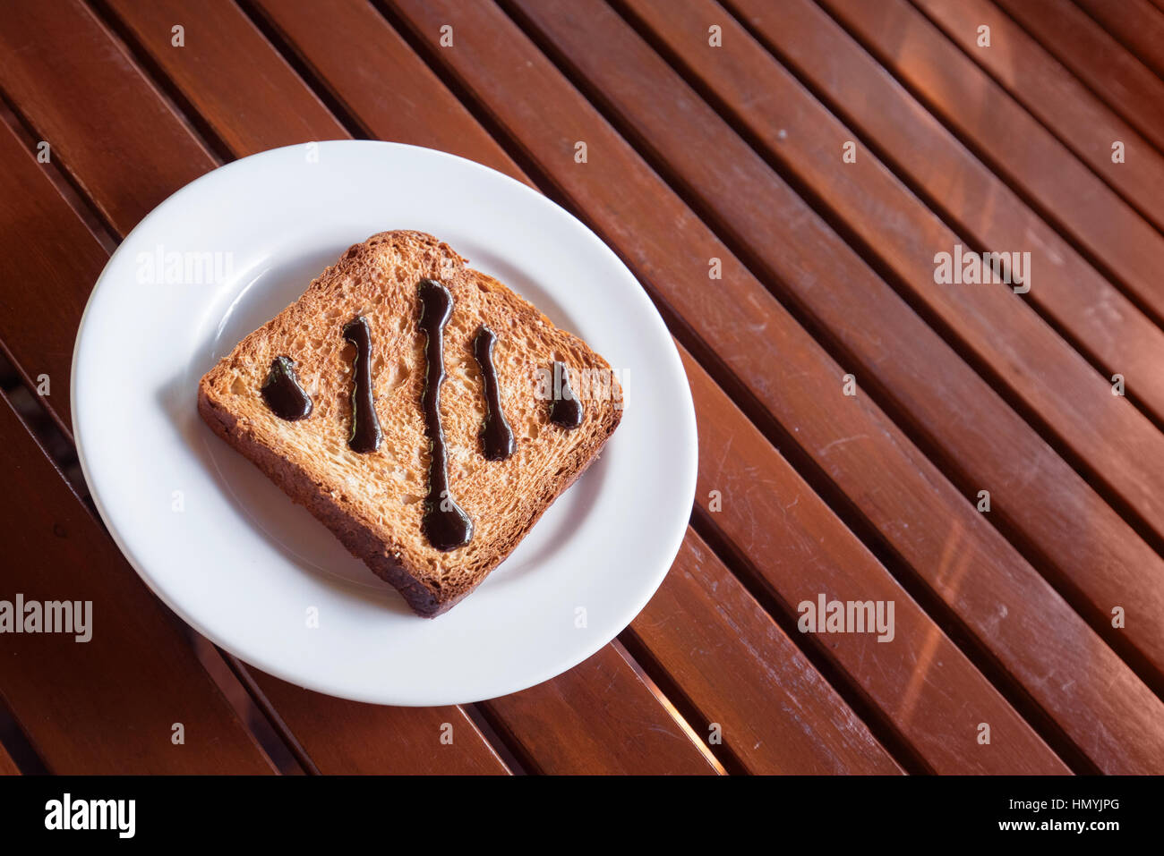 Chocolate Spread on Toast in white disk on wood table window light Stock Photo