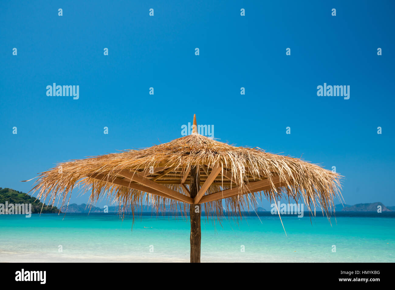 Beach Umbrella made of leafs on white beach in front of Sea day time blue sky wide shot background, Nyaung Oo Phee, Myanmar Stock Photo