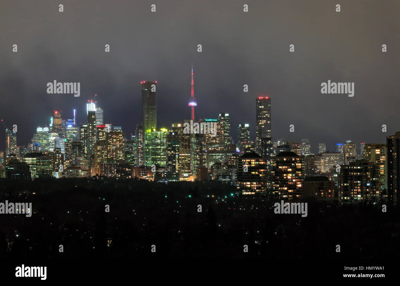 Toronto downtown and midtown skyscrapers with CN Tower, office and residential buildings and hotels, under winter snowy clouds at night Stock Photo