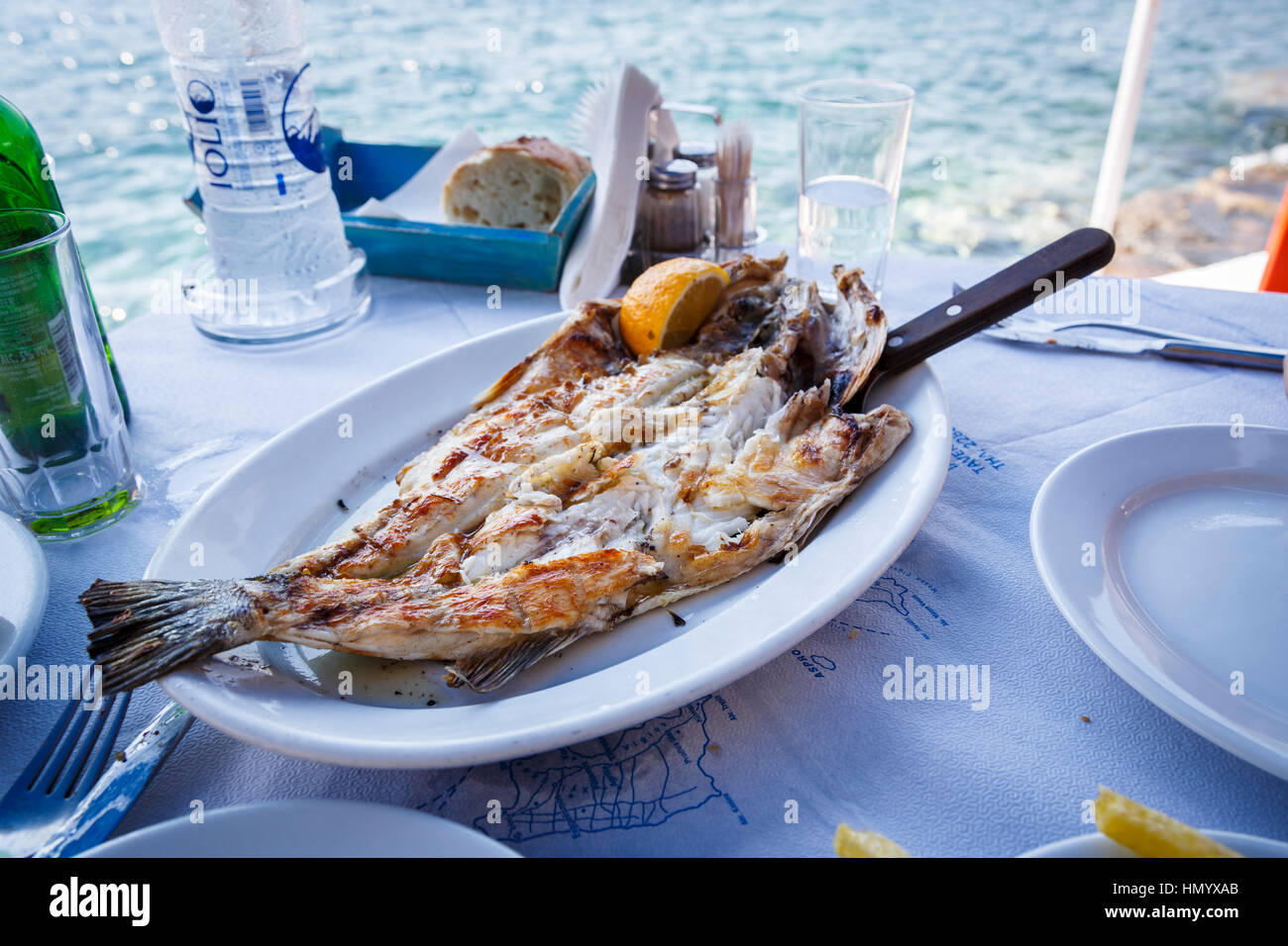 Delicious fresh grilled fish served on a table at a seafront taverna in Ammoudi Bay, Oia, Santorini, a Mediterranean Greek Island in the Cyclades grou Stock Photo