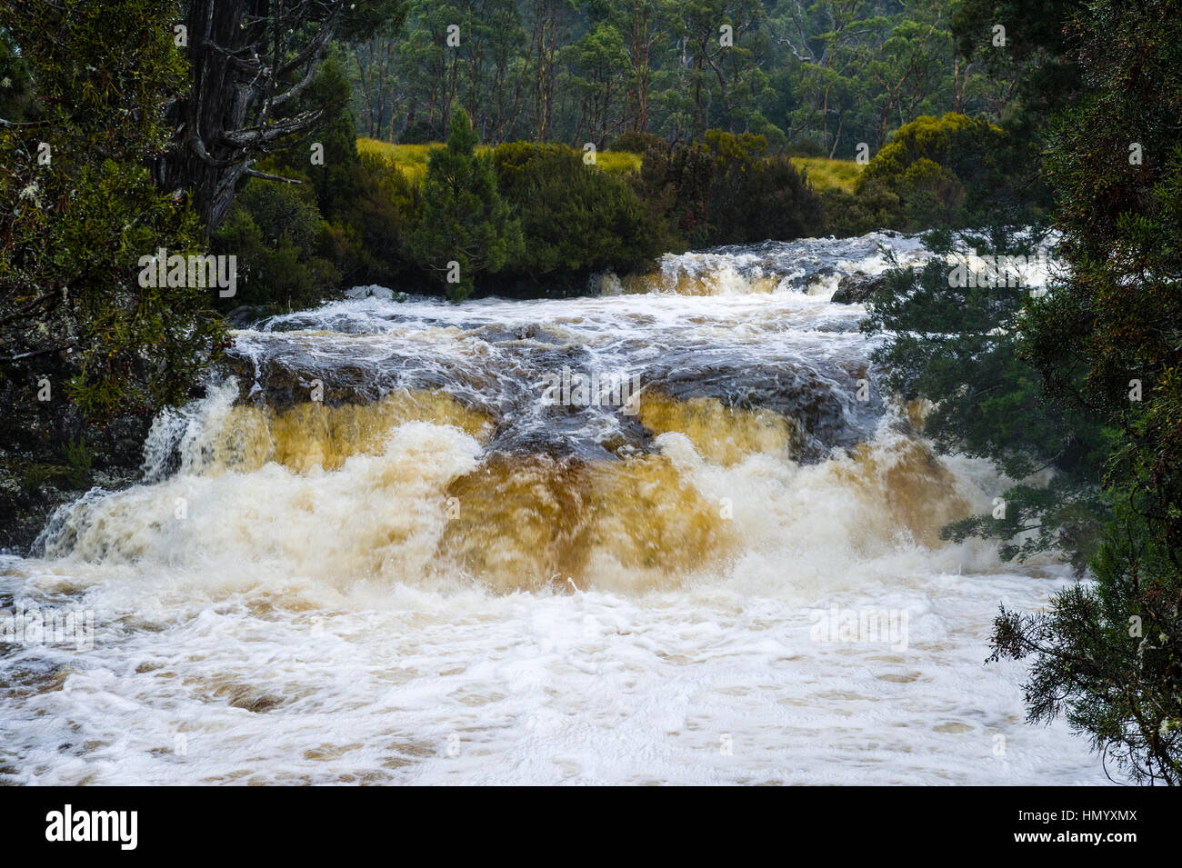 A swollen river cascades over a waterfall during a rainstorm. Stock Photo