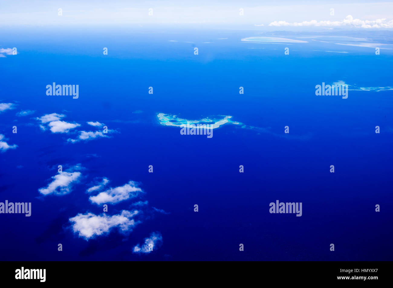 Clouds floating over a deep blue tropical ocean with isolated sandbars. Stock Photo