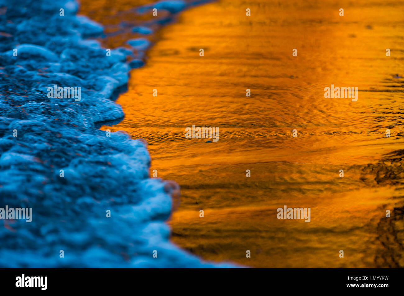 A sandstone cliff reflection in the wet sand on a beach at sunset. Stock Photo
