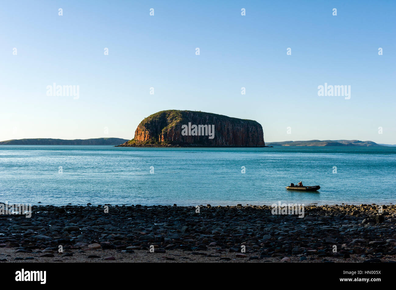 A solitary dingy on the shore if an uninhabited beach at sunset. Stock Photo