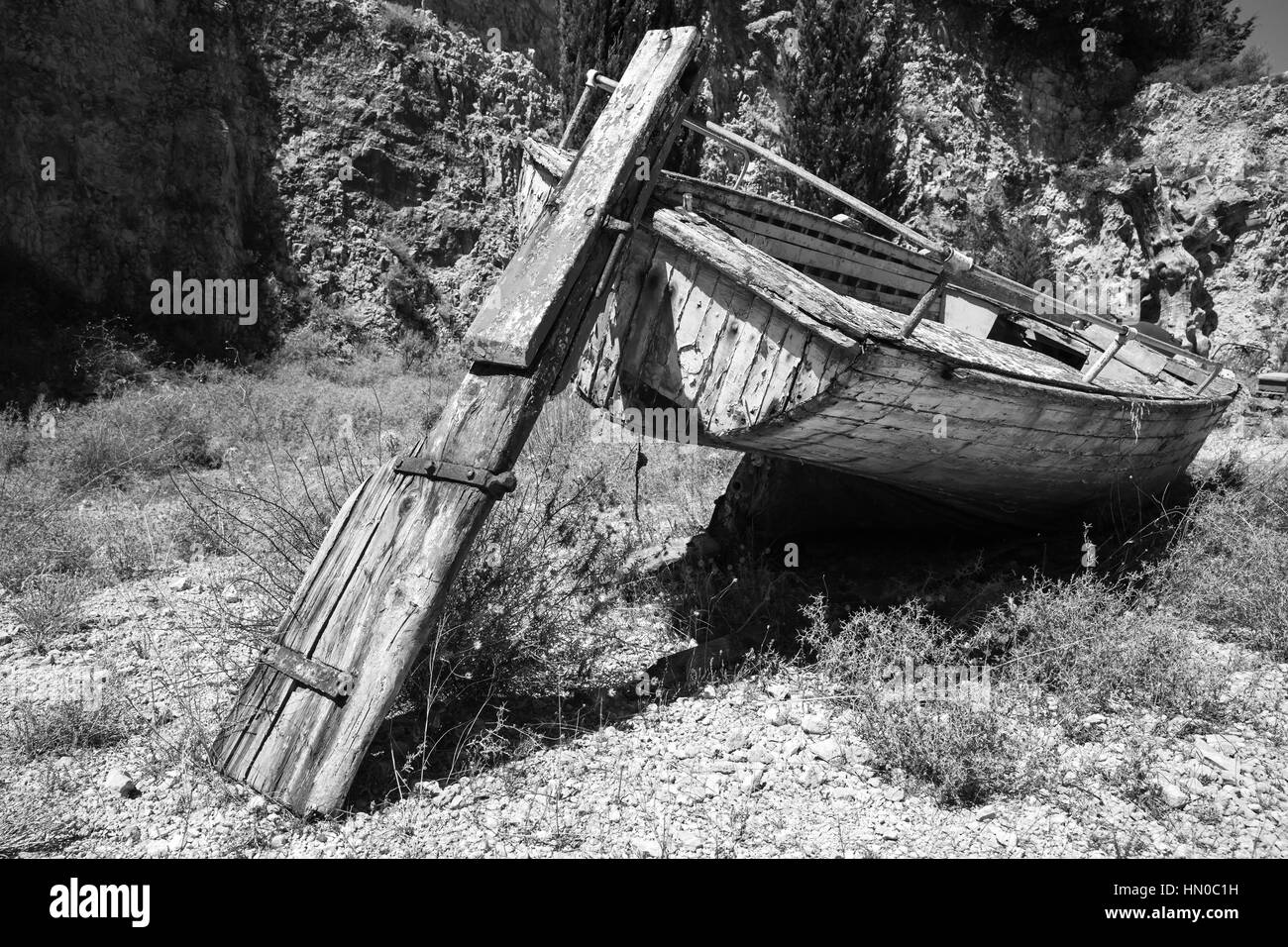 Old abandoned dry wooden fishing boat lays on the ground. Black and ...