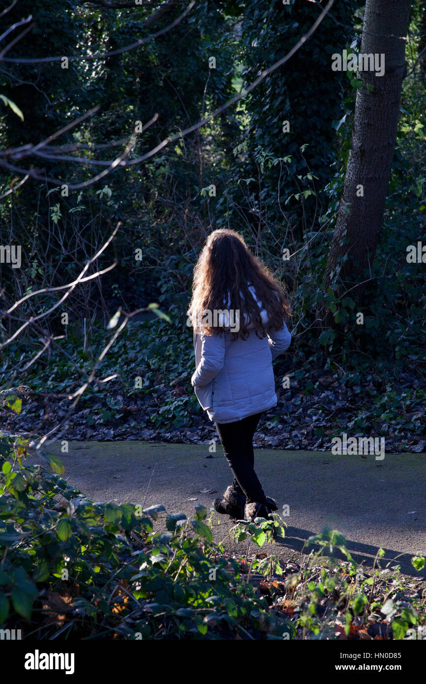 Young female walking away through a park. Rear view. Stock Photo