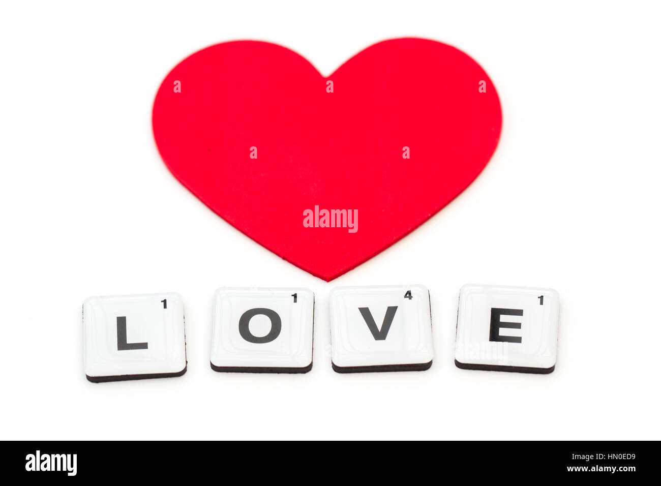 The word LOVE created from letter squares or scrabble tiles on an isolated white background with love hearts and copy space. Stock Photo