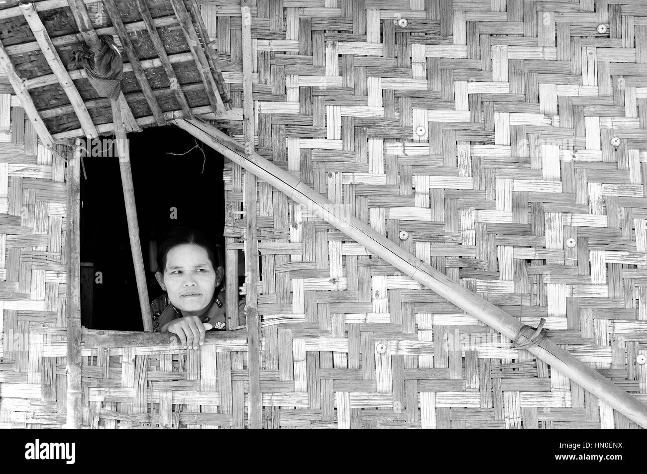 INLE LAKE, MYANMAR - JANUARY 12: Portrait of the Burmese woman in traditional make-up looking through the window from the traditional Burmese cottage  Stock Photo