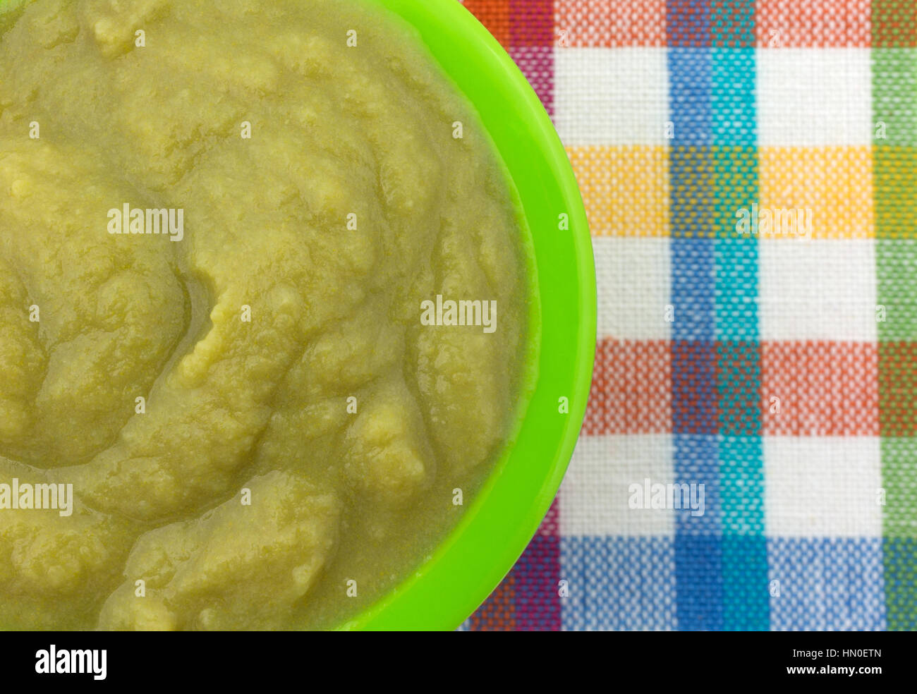 Top close view of a serving of green peas baby food in a small bowl