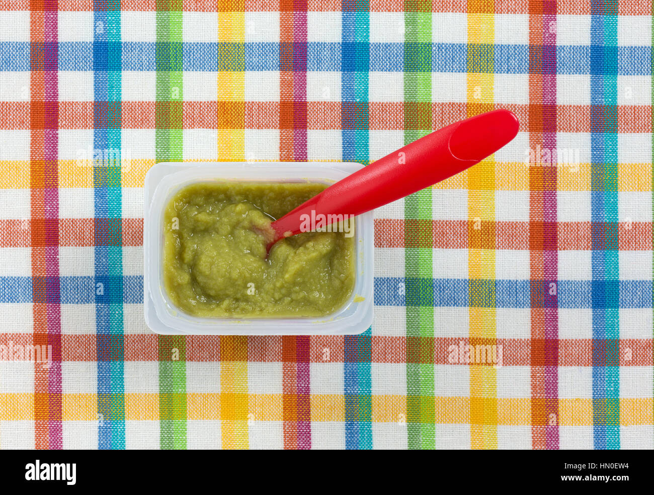 Top view of a serving of green peas baby food in a small plastic