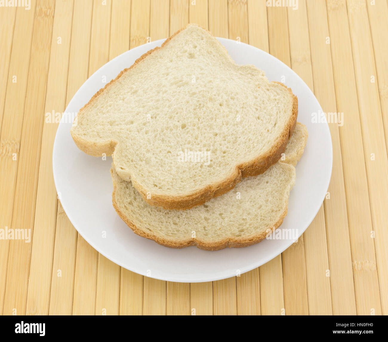 Two slices of English muffin toasting bread on a plate atop a wood