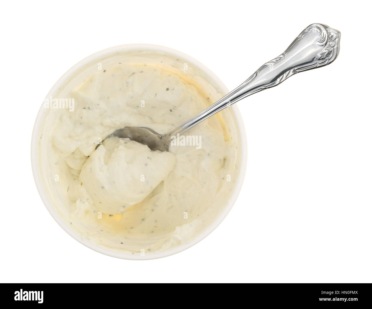 Top view of a container of fresh French onion dip with a spoon inserted into the food isolated on a white background. Stock Photo