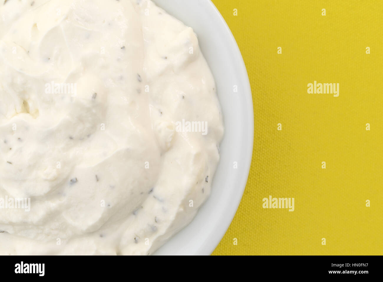 Top close view of  a small bowl filled with fresh French onion dip atop a bright yellow tablecloth. Stock Photo