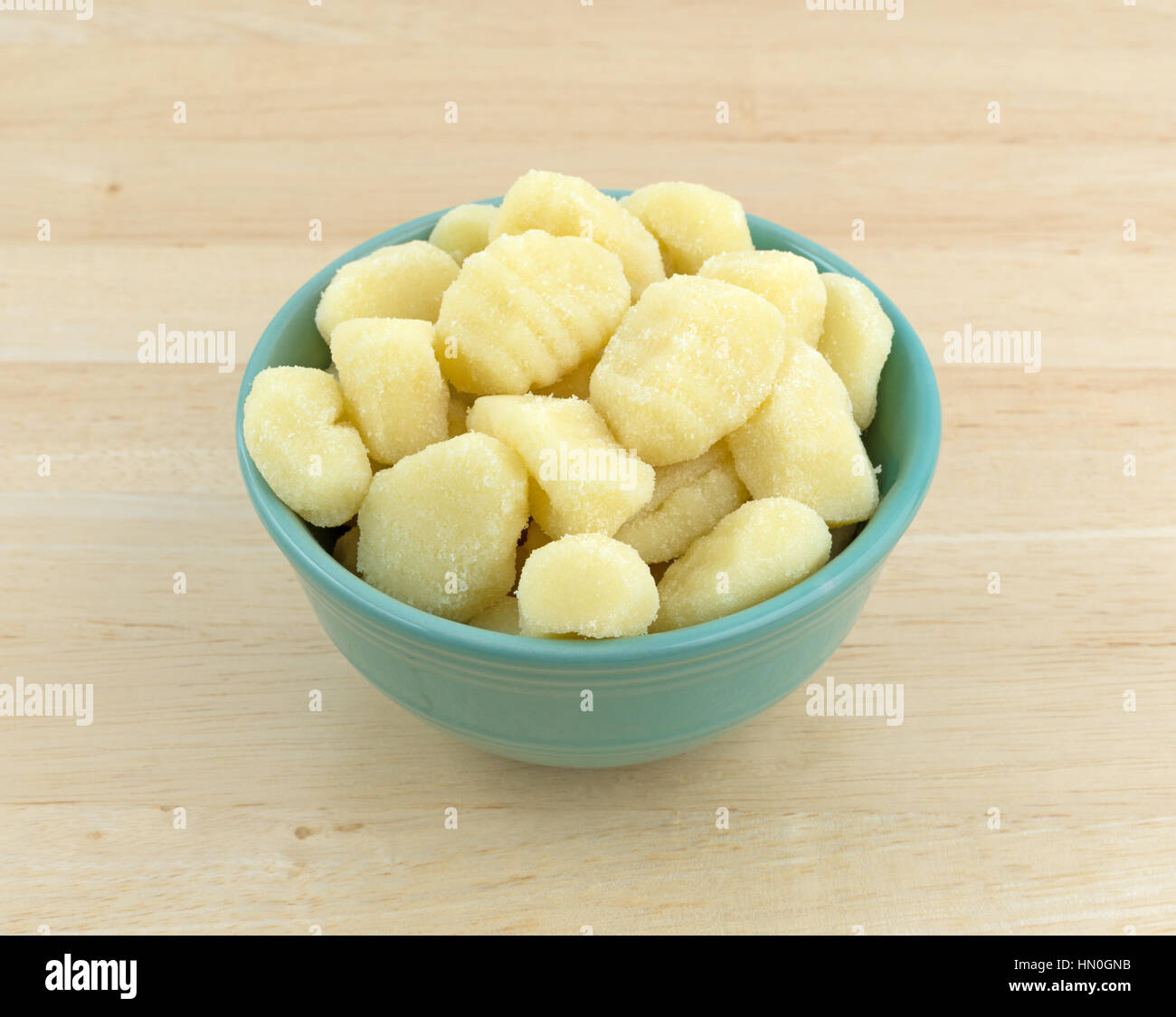Plain potato gnocchi in a green bowl atop a wood table. Stock Photo