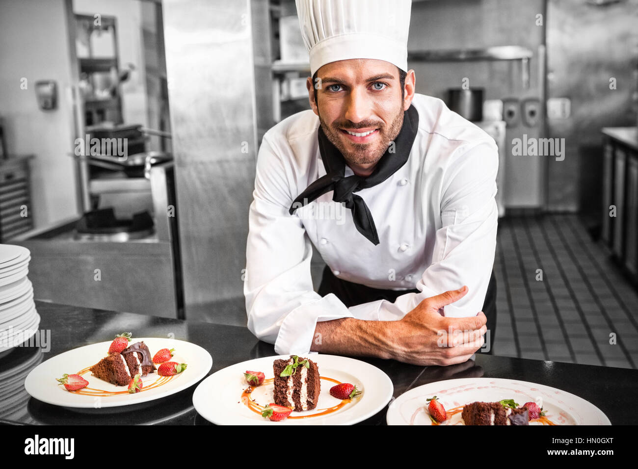 Happy chef looking at camera behind counter of desserts in a