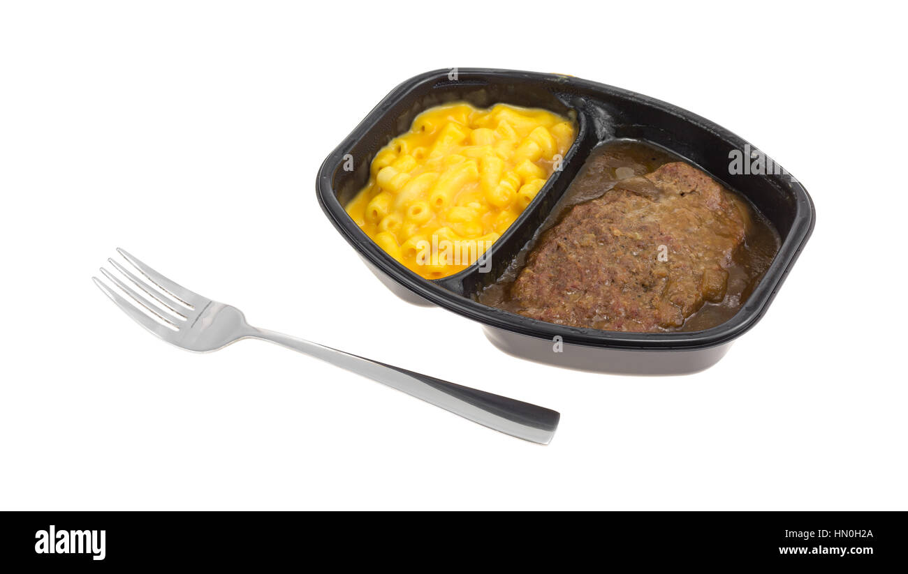 TV dinner meal of salisbury steak with gravy macaroni and cheese in a black tray with a fork to the side isolated on a white background. Stock Photo