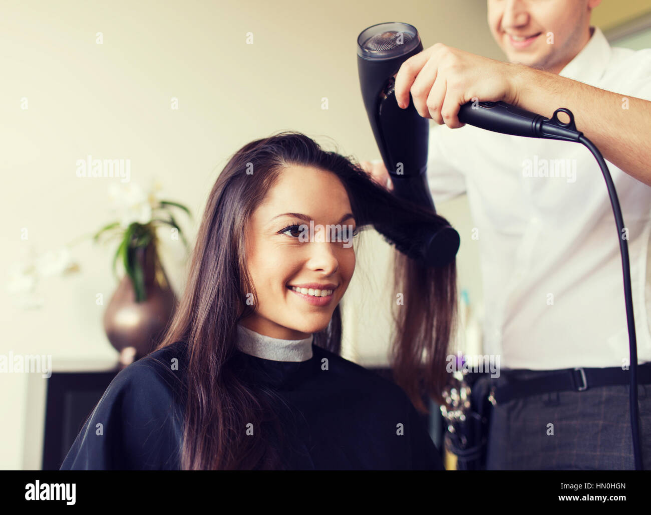 Happy Woman With Stylist Making Hairdo At Salon Stock Photo
