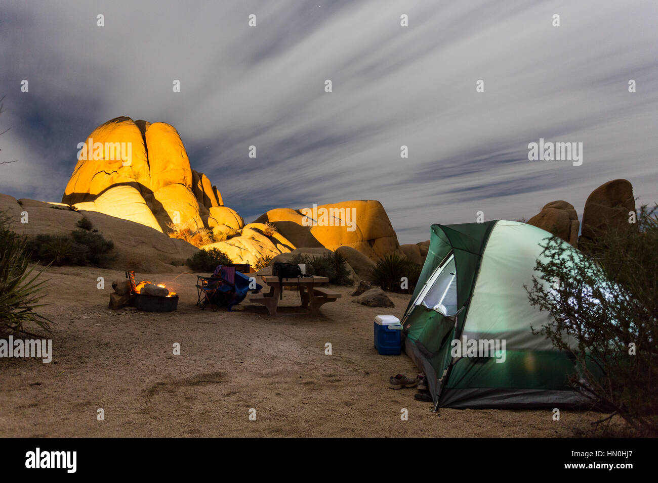 A tent sits next to a campfire at night in a Joshua Tree National Park campsite. Stock Photo