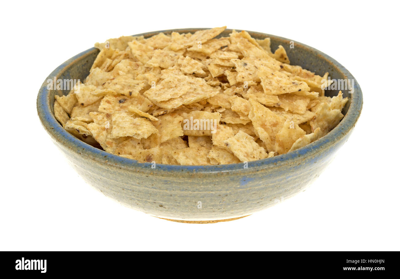 Broken tortilla chips in an old stoneware bowl isolated on a white background. Stock Photo