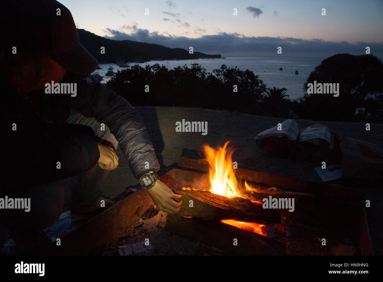 A man tends to a campfire at a site overlooking Two Harbors, Catalina Island. Stock Photo