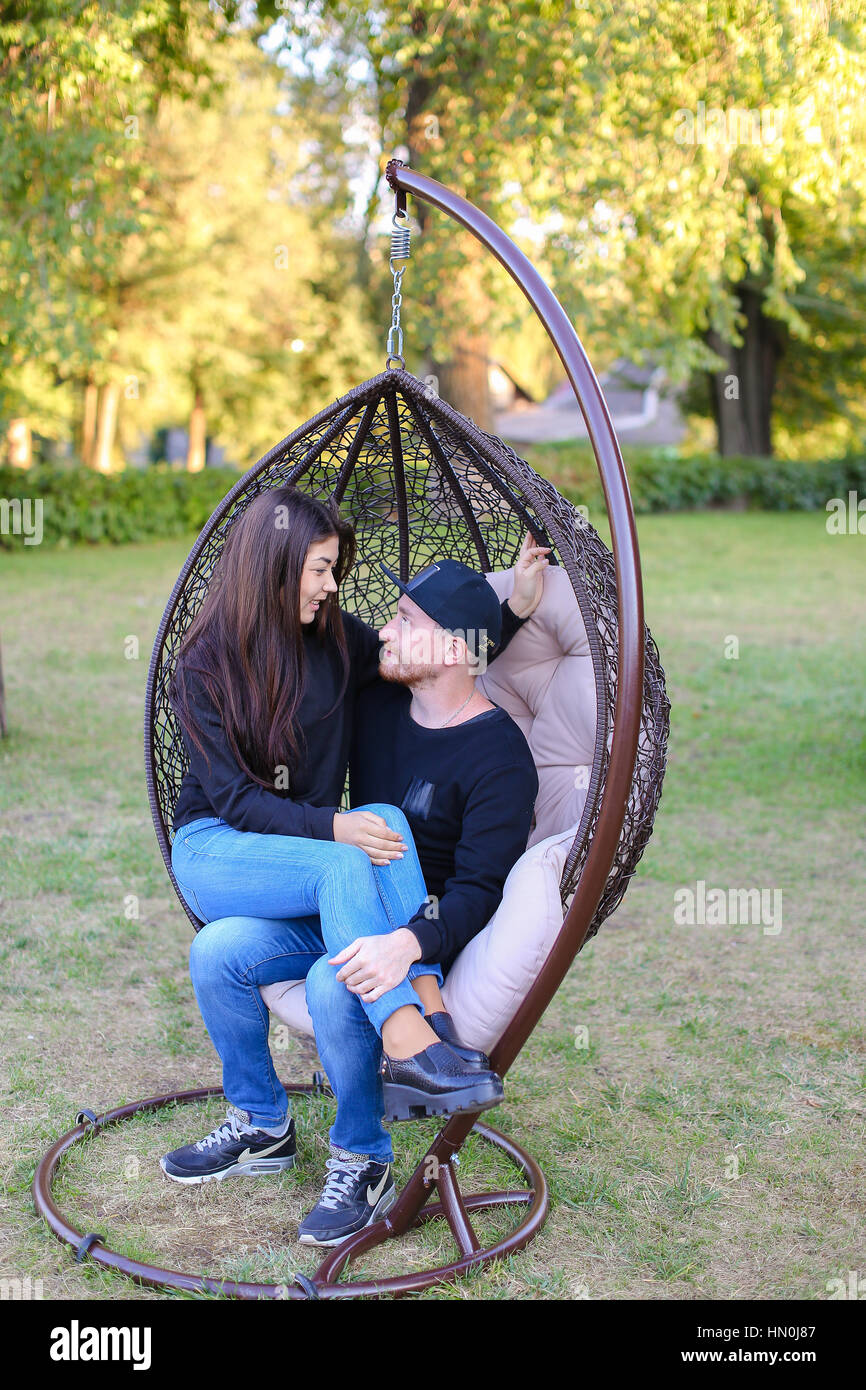 Couple in love swinging on chair in street among large green park,  discussing plans for future, share secrets and jokes, young people hugging  each ot Stock Photo - Alamy