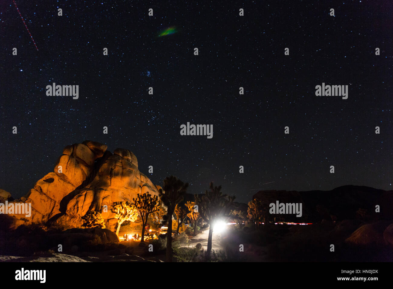 A campfire illuminates the rocks at Hidden Valley Campground in Joshua Tree National Park with several stars overheads. Stock Photo