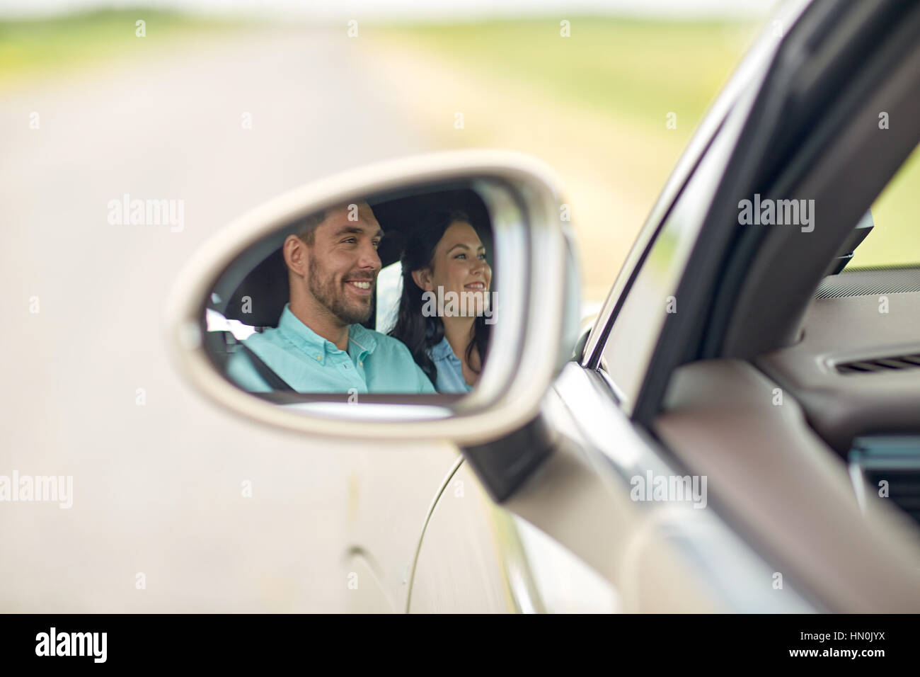 side mirror reflection of happy couple driving car Stock Photo