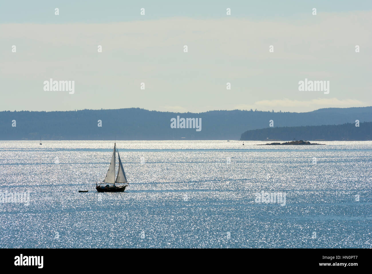 A back lit sailboat on the ocean with Islands in the background. Stock Photo