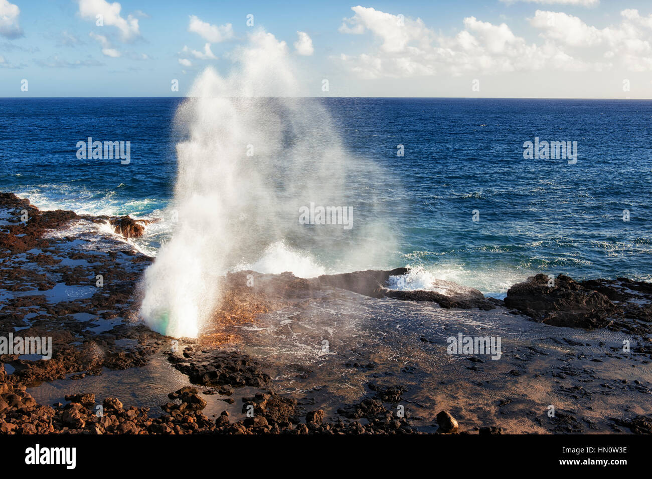 The Pacific Ocean shoots out of the lava blowhole known as The Spouting Horn along the South Shore on Hawaii’s Island of Kauai. Stock Photo